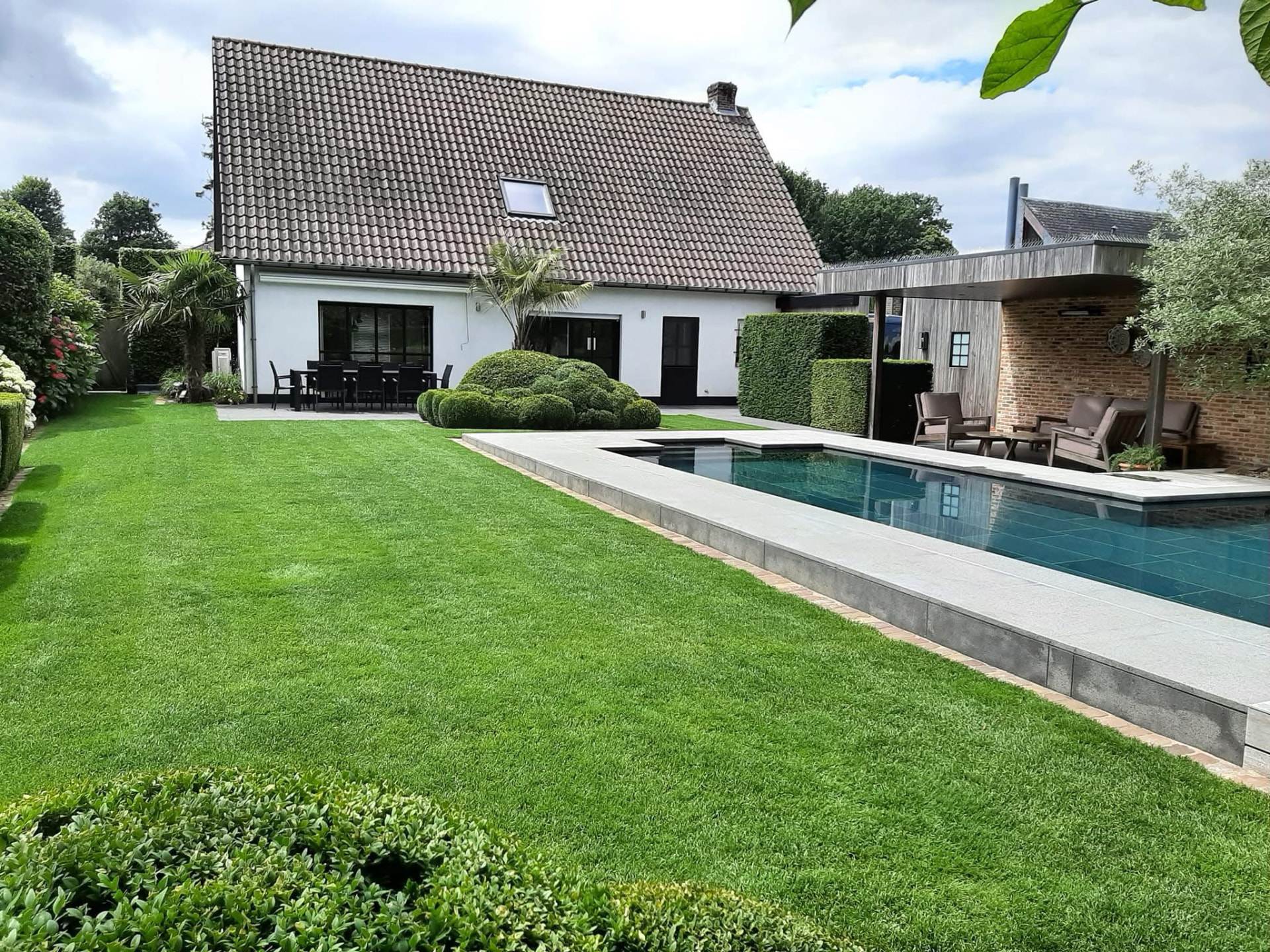 Langwerpig zwembad met gazon, poolhouse en woning